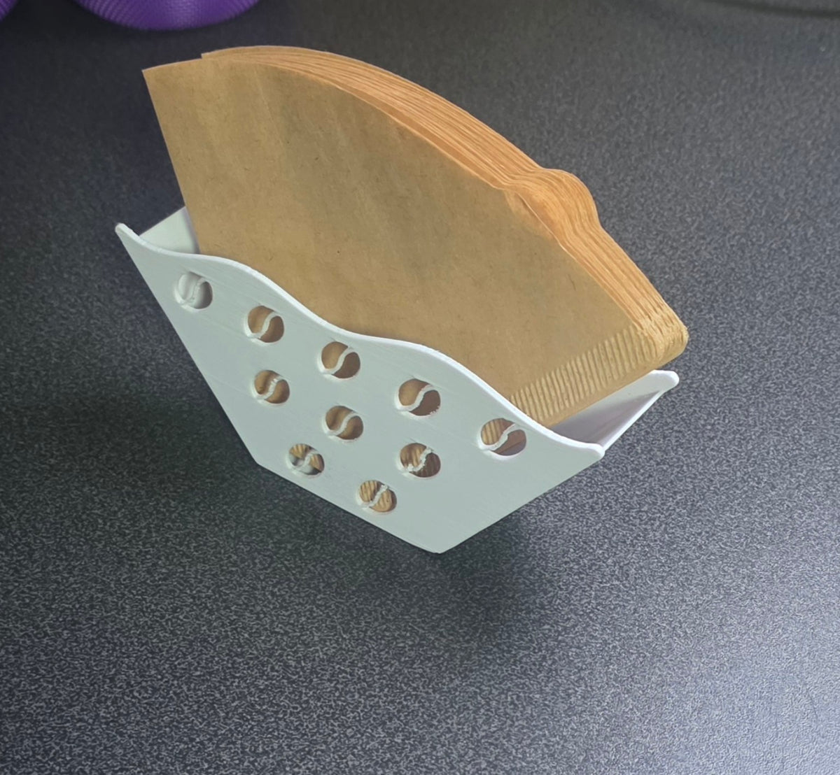 Weißer Kaffeefilterhalter mit Kaffeebohnenmuster, gefüllt mit Papier-Kaffeefiltern.