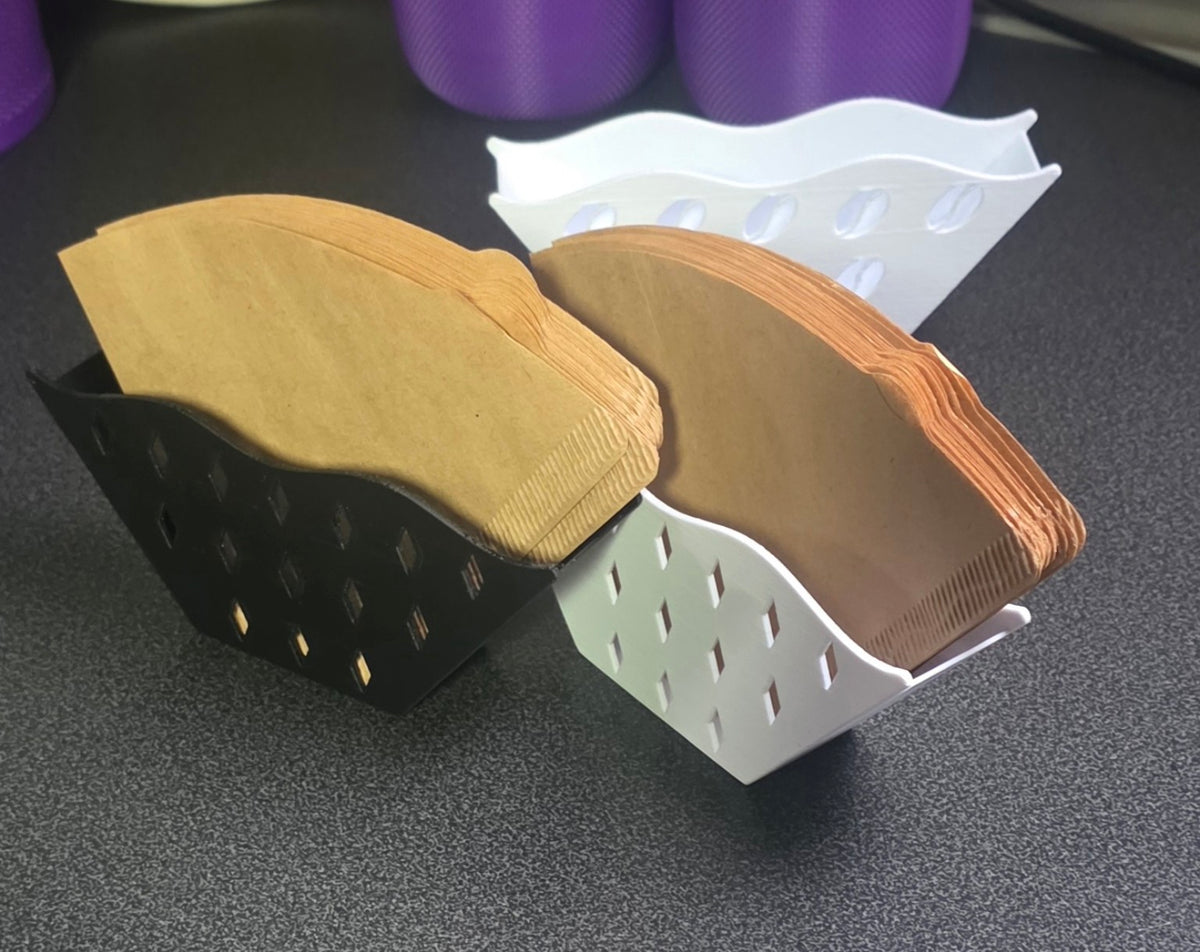 Schwarzer und weißer Kaffeefilterhalter mit Rautenmuster, mit Papierfiltern gefüllt.
